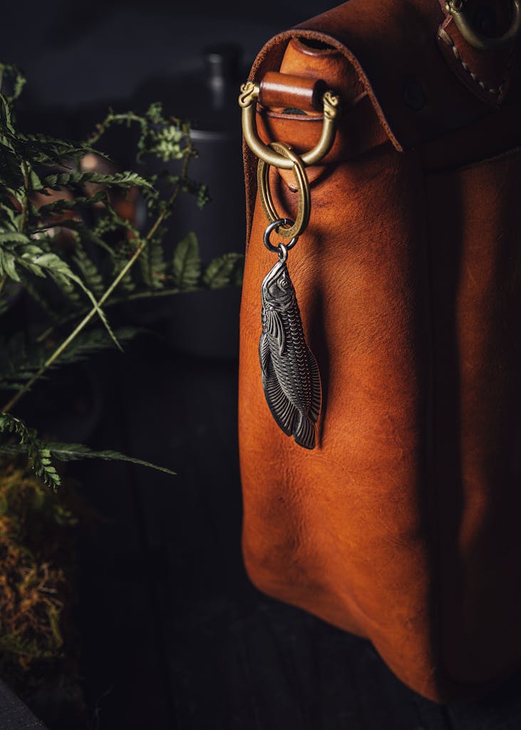 Steel Fish Pendant and Box Opener Hanging from a Leather Bag by the Fern